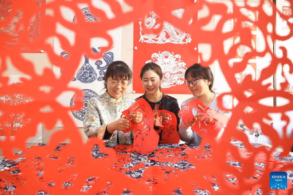 Ge Ying (trái), một nghệ nhân cắt giấy, đang hướng dẫn mọi người làm các tác phẩm cắt giấy chào mừng Năm Tỵ tại thành phố Đường Sơn, tỉnh Hà Bắc, ngày 22/1.