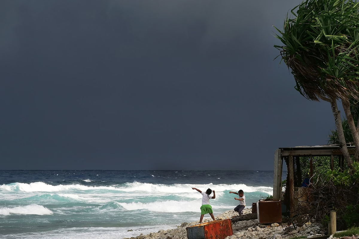 Trẻ em chơi đùa gần biển khi những đám mây giông đang kéo đến hồi năm 2018. 