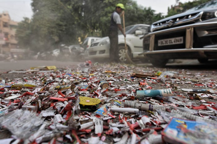 Tình trạng ô nhiễm càng tệ hơn khi Ấn Độ diễn ra lễ hội ánh sáng Diwali - khiến tình trạng đốt pháo trở nên phổ biến. Chính phủ đã thi hành lệnh cấm (đốt pháo) của Tòa án tối cao nhưng người dân phớt lờ. Trong ảnh, một công nhân vệ sinh đang dọn dẹp tàn dư của đống pháo nổ. Ảnh: Getty