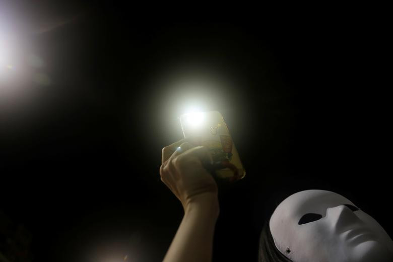 Người biểu tình tuần hành với đèn flash từ điện thoại tại quận Tsim Sha Tsui hôm 5/10 - ngày đầu tiên luật cấm đeo mặt nạ có hiệu lực. (Ảnh: Reuters)