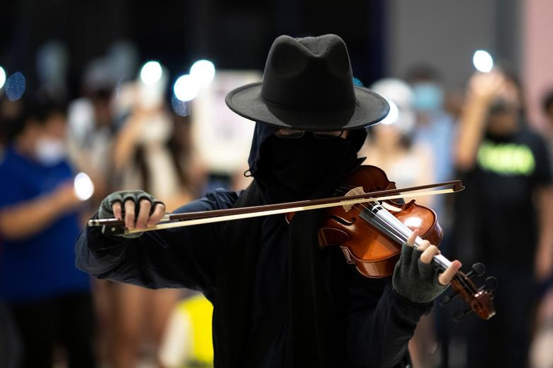 Mặc dù lệnh cấm đã có hiệu lực từ hôm 5/10, người biểu tình vẫn bất chấp đeo mặt nạ để tránh bị nhận diện cũng như bảo vệ bản thân khỏi hơi cay của cảnh sát. Trong ảnh, một người biểu tình đang chơi vĩ cầm bên ngoài khu dân cư Tseung Kwan O, Cửu Long, ngày 7/10. (Ảnh: Reuters)