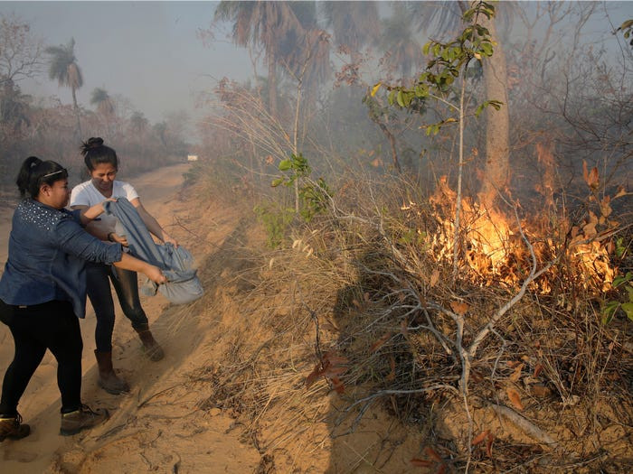 Tuy vậy, phần lớn dụng cụ chữa cháy vẫn khá thô sơ. Trong ảnh, hai tình nguyện viên cứu hỏa đang đổ cát vào đám cháy để dập lửa. (Ảnh: Reuters)