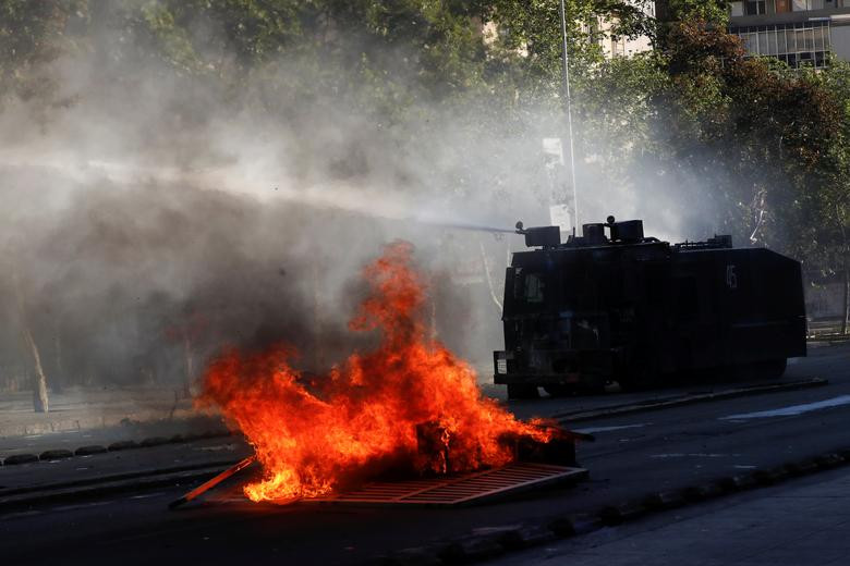 Xe chống bạo động của cảnh sát phun vòi rồng vào người biểu tình tại thủ đô Santiago ngày 30/10.