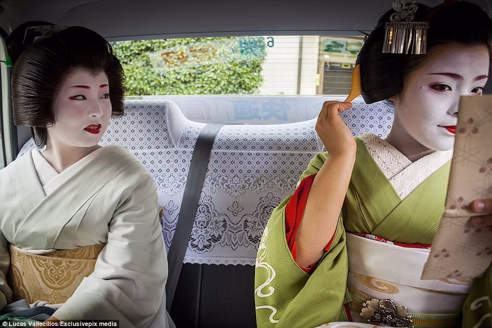 Một Maiko (tức geisha tập sự) hướng mắt nhìn sang người Geiko (geisha thực thụ) đang chỉnh trang lại mái tóc lúc họ ngồi trên taxi đến chỗ làm việc.