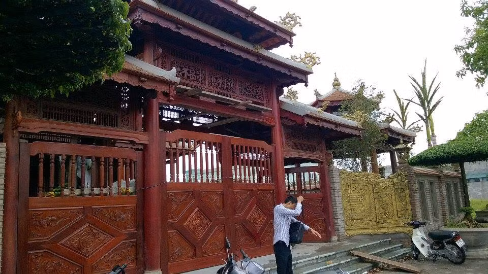 Phần cổng biệt thự được thiết kế theo lối cổ điển phương Đông, với cổng gỗ theo lối tam quan có phần cách điệu nhưng gỗ không phải loại đắt tiền.