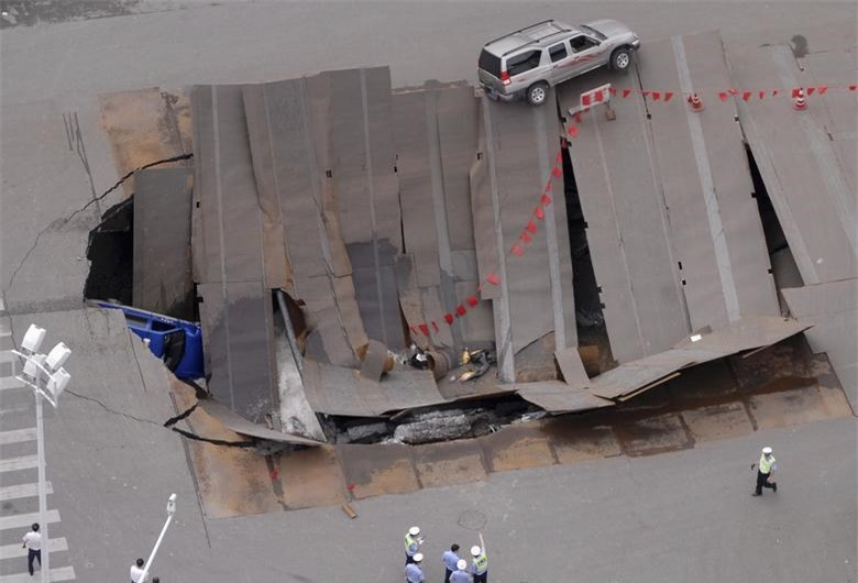 Đoạn ngã tư bị sập ở Hợp Phì, tỉnh An Huy, Trung Quốc vào ngày 8/8/2009. Một chiếc taxi và một vài xe máy bị lọt "hố tử thần". Ảnh: Reuters.