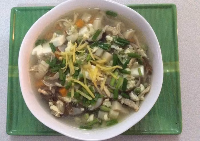 Cho nước vào nồi đun sôi. Khi nước sôi thì cho đậu Hà lan, thịt và các loại nguyên liệu vào đun sôi, nhỏ lửa. Đun khoảng 3p thì cho trứng vào sôi khoảng 1 phút nêm thêm nước vừa ăn và sau cùng là cho hành lá, dầu mè và gừng vào. Tô canh nóng, thơm ăn rất vừa miệng và rất bổ dưỡng, có thể ăn như món súp rau cũng tuyệt. Ảnh: Cookpad.