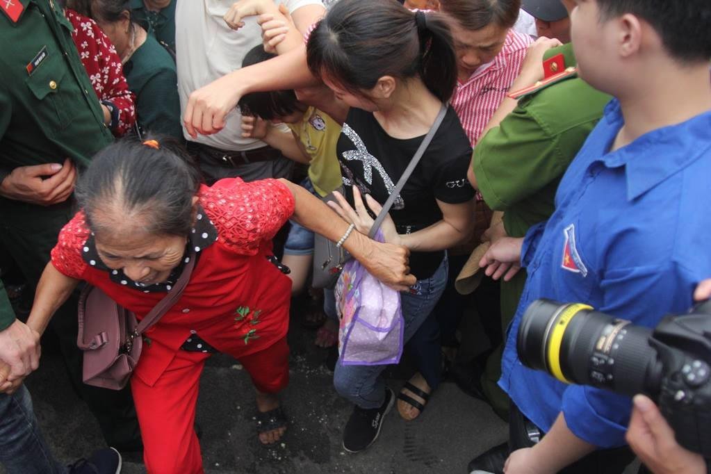 Một người lớn tuổi khó khăn vượt qua biển người.