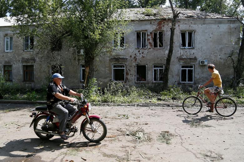 Người dân đi qua tòa nhà bị hư hại do trúng đạn pháo ở vùng ngoại ô thành phố Donetsk tháng 6/2019.
