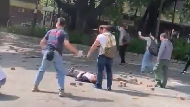 Đoạn video ghi lại vụ việc được đăng tải cho thấy hai nhóm người bịt mặt vẫn tiếp tục ném gạch vào nhau sau khi cụ ông này ngã xuống đường. Ảnh: CNA.