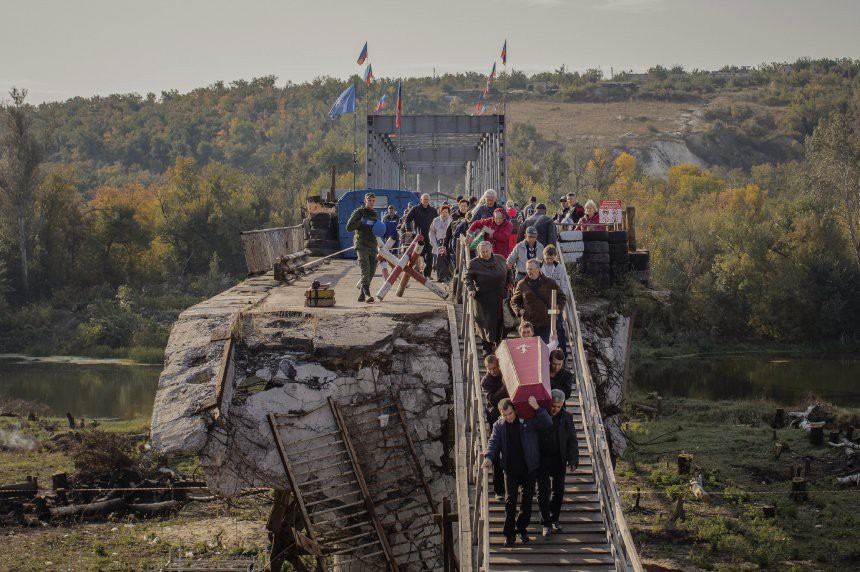 Trong khi đó, cuộc sống của người dân vẫn diễn ra bình thường tại vùng chiến sự này. Trong ảnh là một đám ma đi qua cây cầu bắc trên sông Luhan, một ranh giới tự nhiên giữa hai vùng do hai bên kiểm soát. Ảnh: Spiegel. Mời độc giả xem thêm video về một vụ nổ kho đạn ở Donetsk (Nguồn: VTC14)