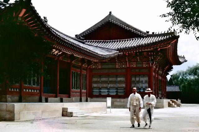 Hai người đàn ông Hàn Quốc ăn vận trang phục truyền thống đi ngang qua một cung điện.