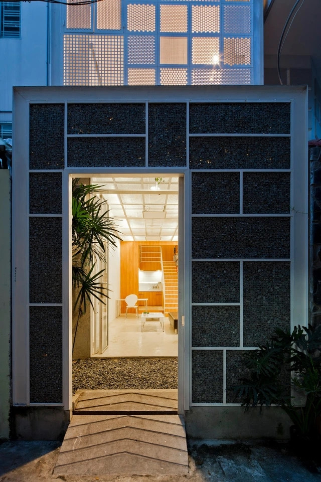 Đáng chú ý nhất là bức tường trước nhà được "dệt bằng sỏi" kẹp giữa 2 tấm lưới sắt. Thay vì đổ bê tông, gia chủ chọn cách rải lớp đá răm dọc lối vào nhà.