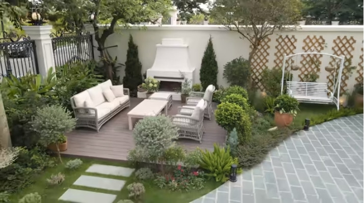 Khuôn viên bên ngoài biệt thự trồng nhiều cây xanh, có sofa để cả nhà thư giãn.