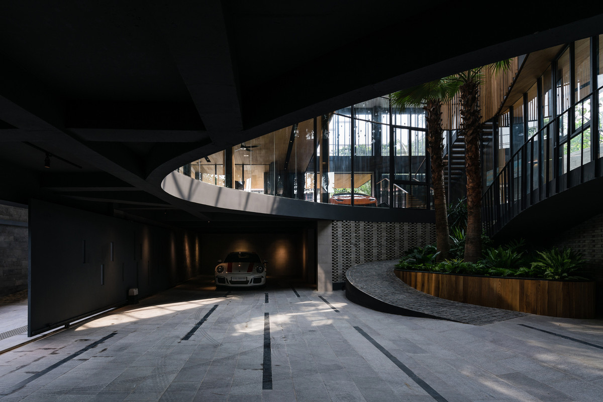 Lối vào chính bắt đầu từ đây, đi theo một đoạn đường dốc xuyên qua không gian mở tràn ngập cây xanh, dẫn lên tầng trên với không gian sinh hoạt, nhà bếp và phòng ăn mở.