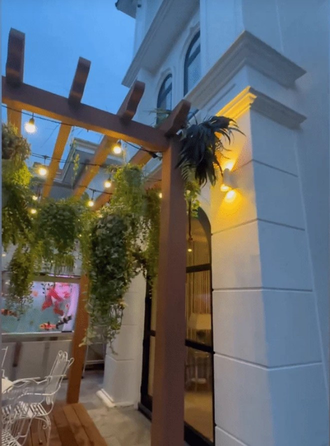 Khoảng sân nhỏ phía trước nhà được bài trí một bộ bàn ghế cà phê màu trắng thanh lịch.