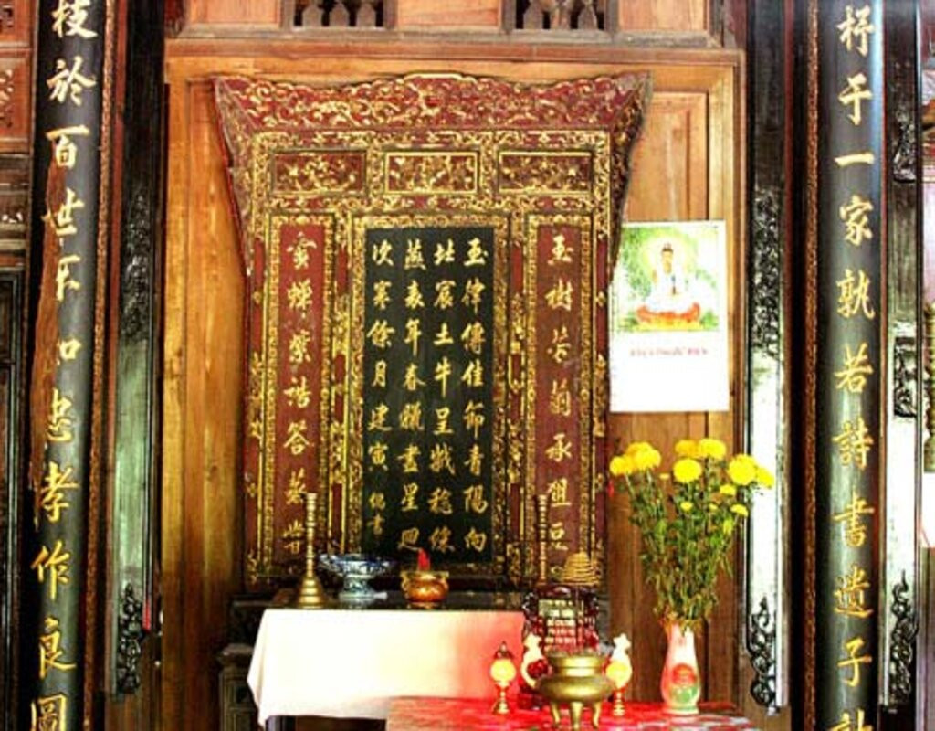 Bàn thờ gia tiên đặt theo lối kiến trúc bàn thờ người Việt, ở giữa là án thờ, với bức khánh thờ chạm khắc hoa văn cổ, một bản văn tự chữ Hán đặt vị trí giữa khánh thờ. Ảnh: Baophapluat
