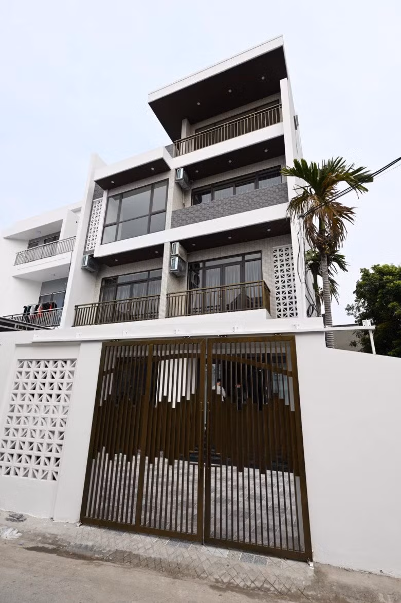 Căn nhà có gam màu trắng chủ đạo, kết hợp với màu đen và màu nâu vàng của cổng nhà.