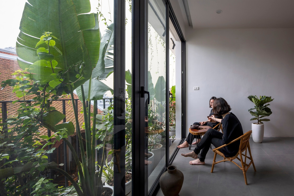 Tầng 2 được chia làm 2 không gian, kết nối với nhau bởi khoảng sân nhỏ đầy màu xanh.