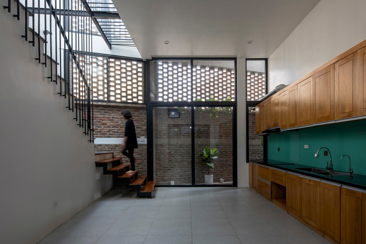 Cạnh khu vực bếp là cầu thang dẫn lên sảnh hiên được xây dựng với mái kính và bức tường gạch lỗ, tạo cảm giác thoáng sáng.