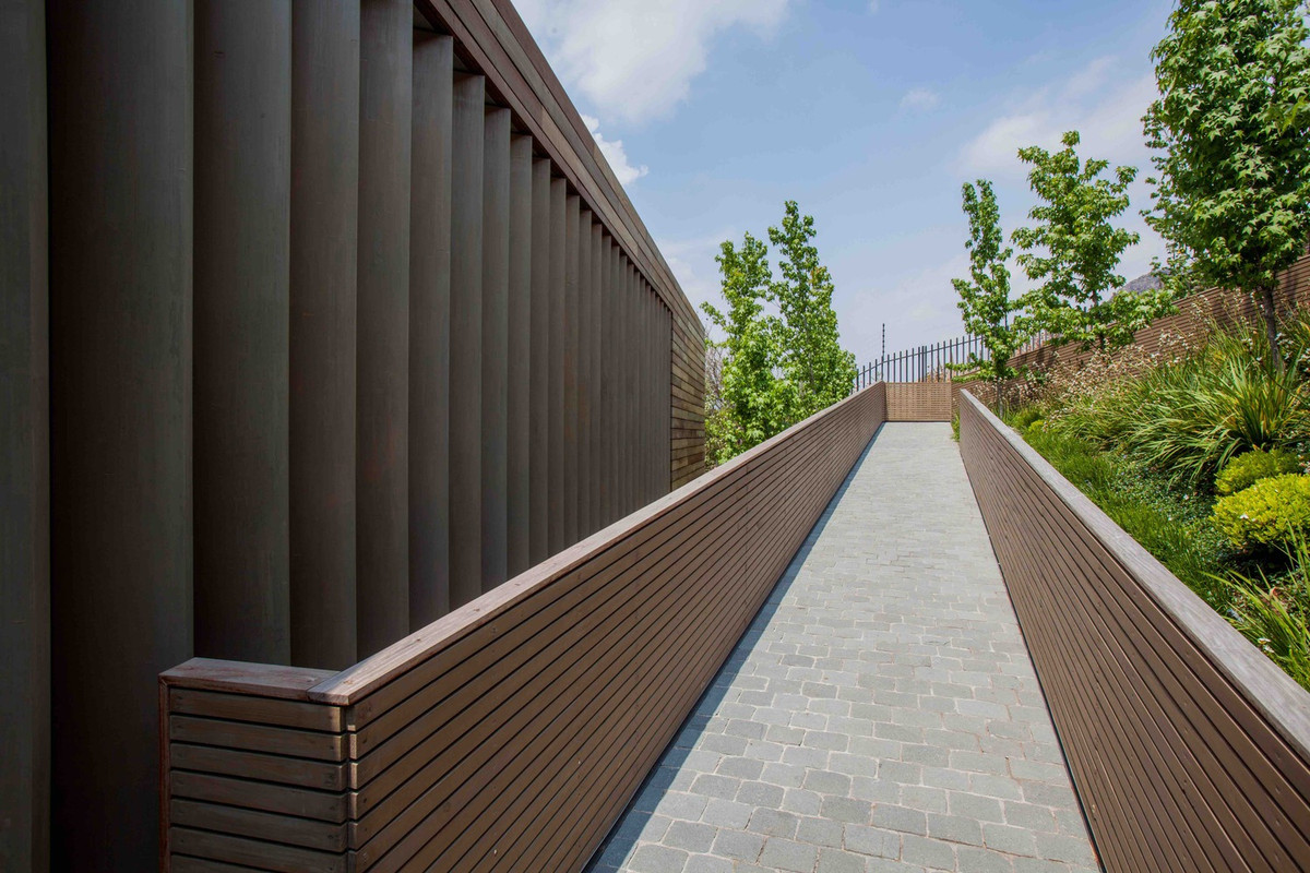 Lối vào nhà được lát gạch so le chống trơn trượt hiệu quả, 2 bên là lan can ốp gỗ sang trọng. Nguồn ảnh: Archdaily