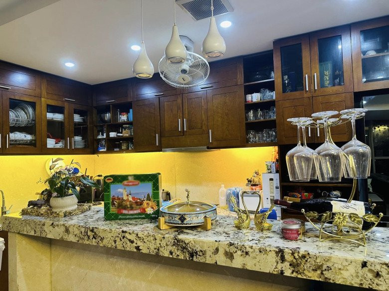 Khu bếp gọn gàng với tủ màu nâu trầm, bàn đảo mặt đá cùng nhiều món đồ decor đẹp mắt.