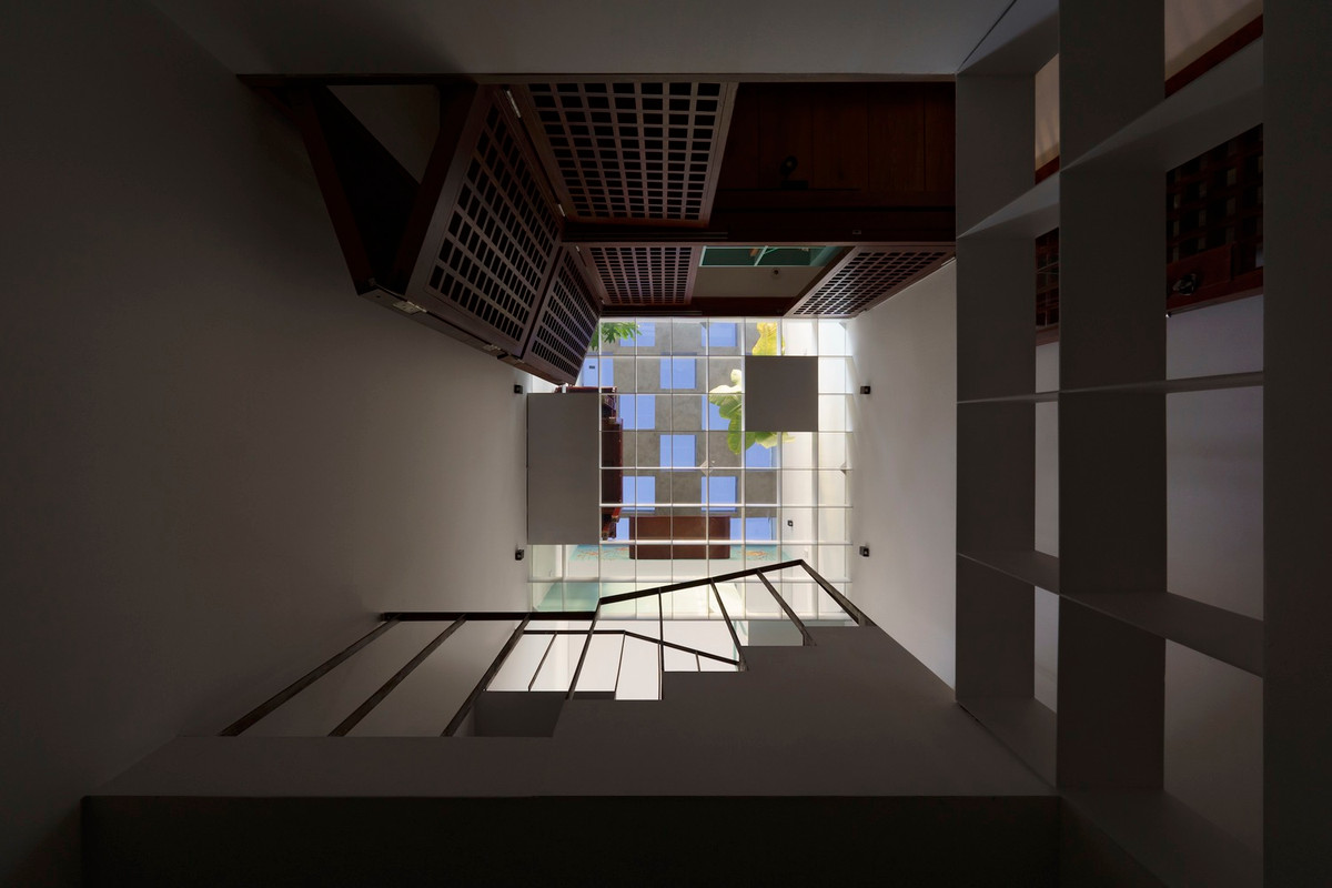 Thông tầng chính giữa nhà kết hợp sàn kính giúp đưa ánh sáng tự nhiên xuống tầng trệt.