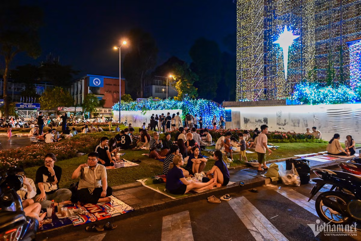 Nhiều bạn trẻ trải thảm, ngồi uống nước và chuyện trò ở vườn hoa phía trước nhà thờ.