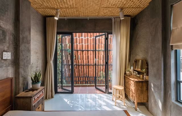 Phòng ngủ thoáng đãng, nổi bật với bức tường bê tông thô.