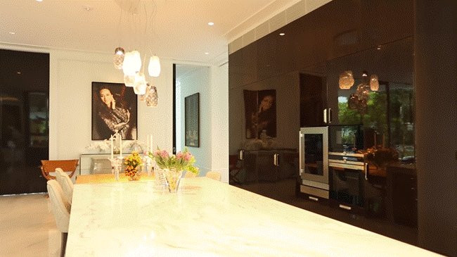 Khu bếp mở được thiết kế với hệ tủ âm tường cao đến trần để đựng bát đĩa, ly rượu,... Ảnh: Hello