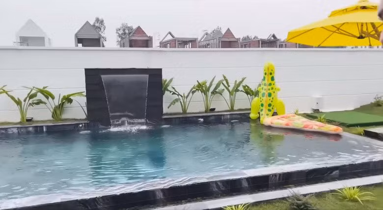 Bể bơi có thác nước, cây xanh tạo cảnh quan độc đáo.