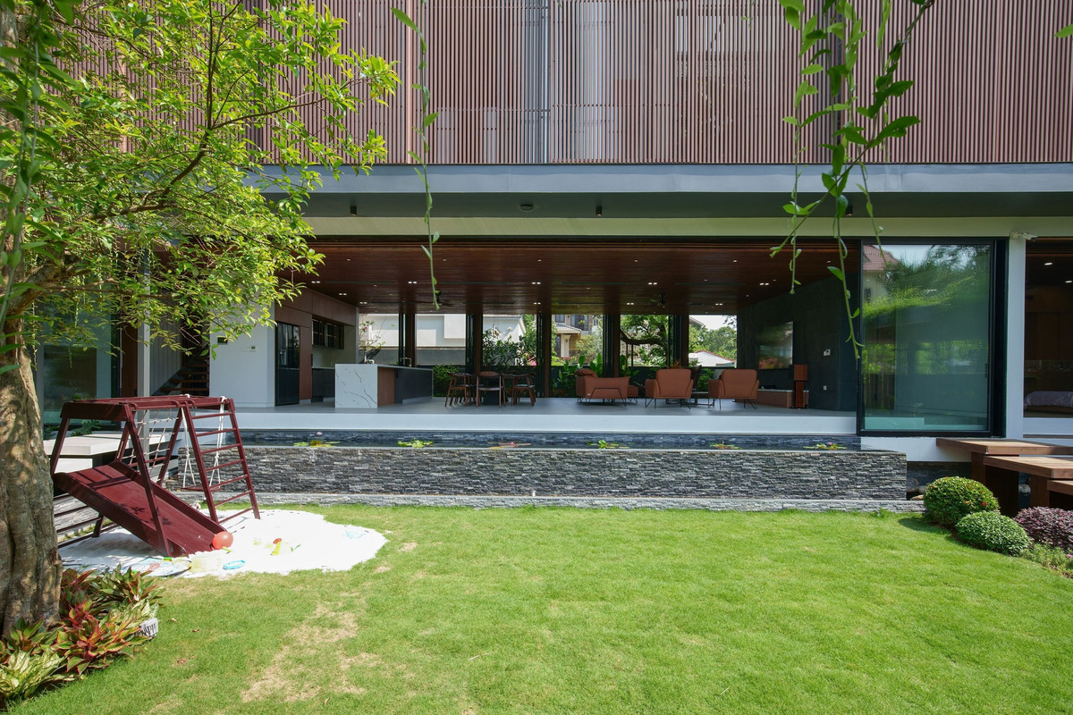 Lớp bảo vệ bên ngoài là hệ thống lam che nắng bằng nhựa tái chế và gỗ bao phủ toàn bộ tầng 2, giúp hạn chế tia UV có hại vào giờ cao điểm và tăng tính riêng tư.