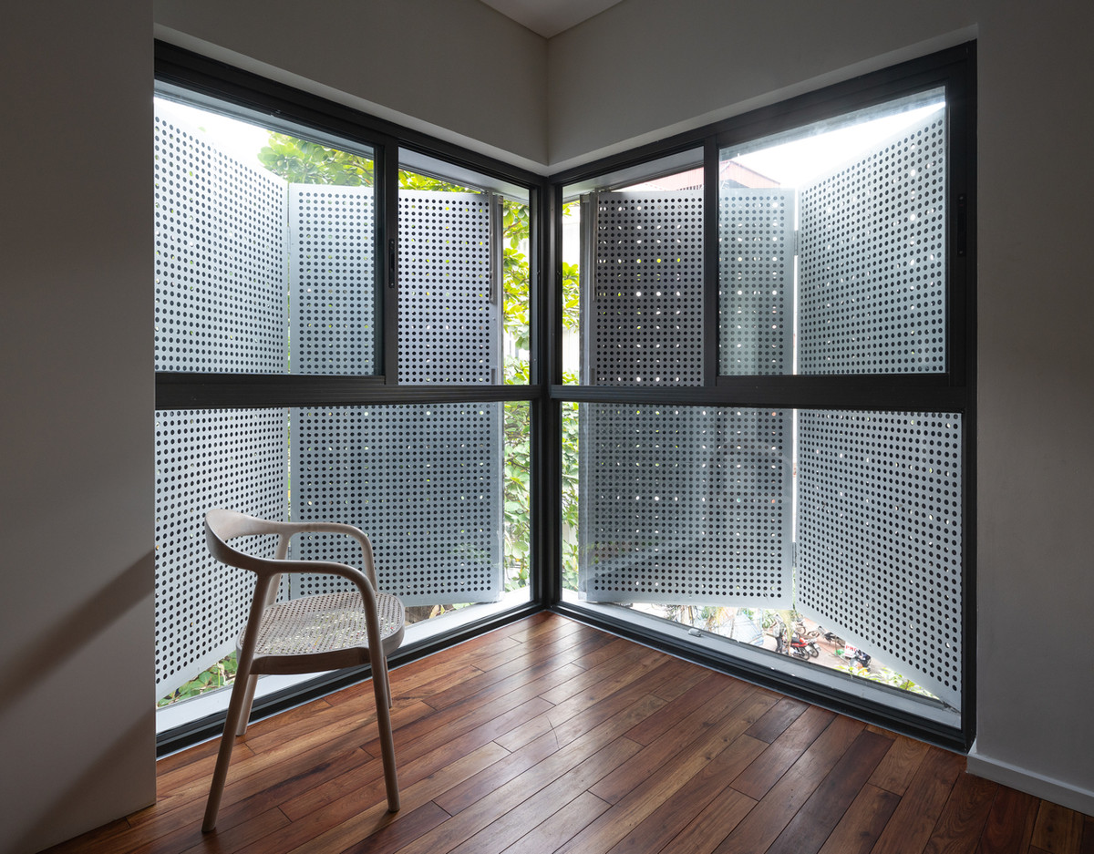 Tấm ốp xi măng nguyên tấm bao bọc toàn bộ phần tường bên ngoài và tấm ốp xi măng đục lỗ cho ô cửa sổ ở góc vuông tầng 2.