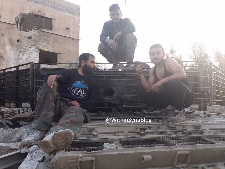 Mạng WithinSyriablog mới đây đăng tải hình ảnh về một chiếc xe tăng T-72 nâng cấp của Quân đội Syria bị thủng một lỗ lớn ở đuôi tháp pháo. “Tác giả” của lỗ thủng đó được cho là súng chống tăng RPG-29 của phiến quân Syria. Rất may, chiếc xe tăng vẫn nguyên vẹn sau phát bắn, nhưng chắc chắn nó đã bị hư hỏng. Không rõ số phận của kíp lái – tuy nhiên từ dấu vết phát bắn, có thể nhận định ít nhất 1-2 trong 3 người sẽ sống sót. Nguồn ảnh: WithinSyriablog