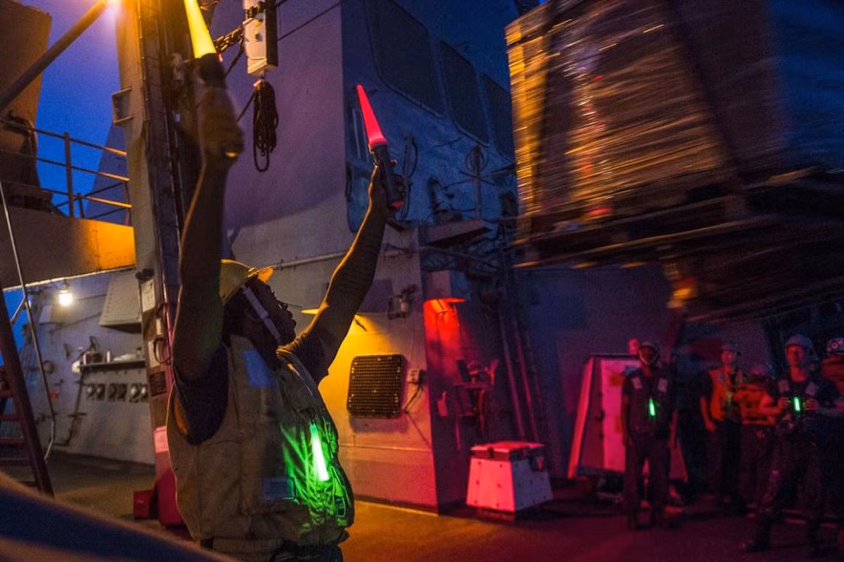 Thủy thủ hoa tiêu đang chỉ dẫn người lái cần cẩu đưa hàng từ USNS Laramie sang tàu hộ vệ tên lửa USS Stout. Hai tàu này thuộc Hạm đội 5 Hải quân Mỹ đang thực hiện nhiệm vụ tại Vịnh Ba Tư. Nguồn ảnh: Businessinsider.