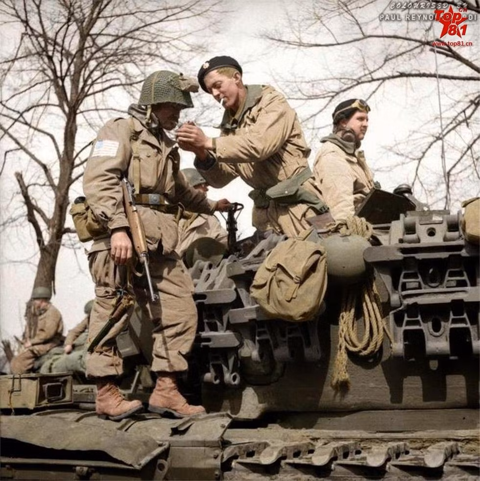Binh lính Mỹ và kíp lái xe tăng Anh chia sẻ từng điếu thuốc. Trên chiến trường, mối quan hệ của các kíp lái xe tăng và các binh lính bộ binh là rất khăng khít vì xe tăng cần bộ binh đi cùng vào trận đánh để bọc cánh và bọc hậu còn bộ binh thì cần xe tăng để hút bớt hỏa lực của đối phương và quan trọng hơn nữa là để... đỡ phải đi bộ trong những đợt hành quân xa. Nguồn ảnh: Top81.