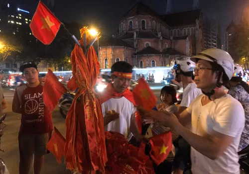 Những người kinh doanh cờ, dây đeo được dịp bán đắt hàng.