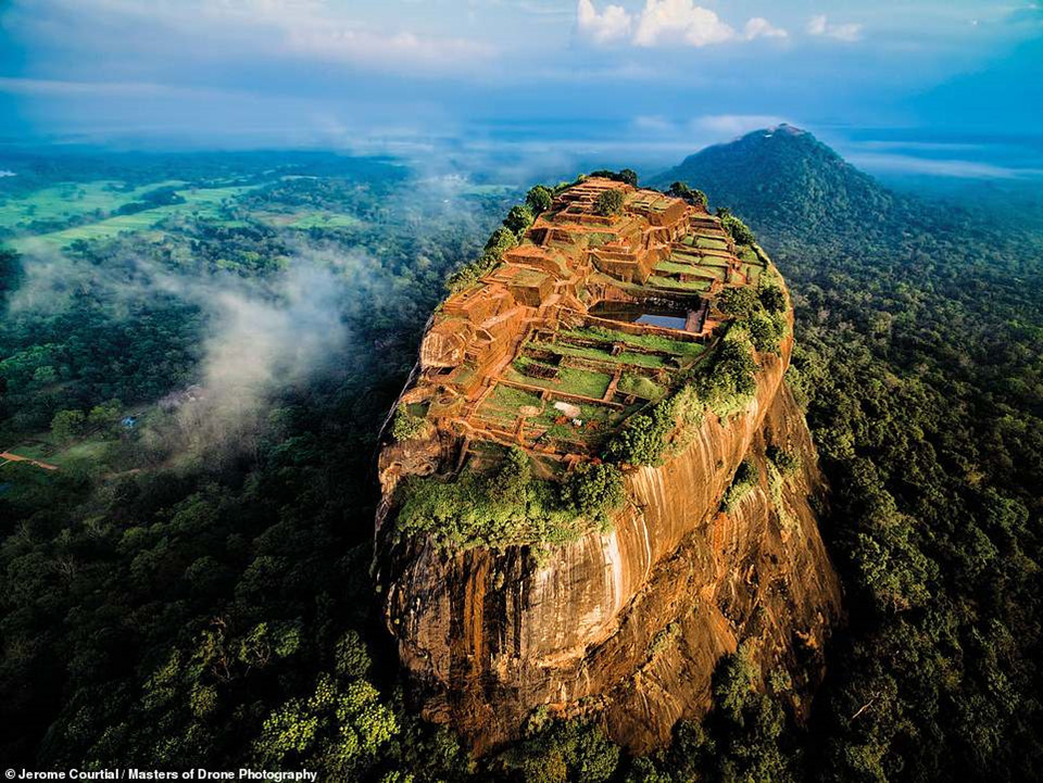 Sigiriya ở Sri Lanka là phế tích cung điện cổ được xây trên núi đá cao 370 m dưới triều đại vua Kassapa I (477-495). Jerome Courtial, tác giả của bức ảnh, cho biết anh gặp khó khăn khi tìm chỗ bay fly cam. Bao quanh Sigiriya là khu rừng rậm với nhiều loài động vật hoang dã sinh sống. "Tôi khá may mắn khi có thể bắt ánh sáng đẹp. Những đám mây nhỏ bên trái khiến cho bức hình trở nên dễ chịu hơn", anh nói.