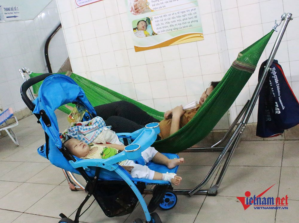 Nguyên nhân là do phòng bệnh có số lượng bệnh nhi quá đông cùng với thời tiết nắng nóng nên nhiều người chấp nhận ra ngoài hàng lang mắc võng, trải chiếu nằm.