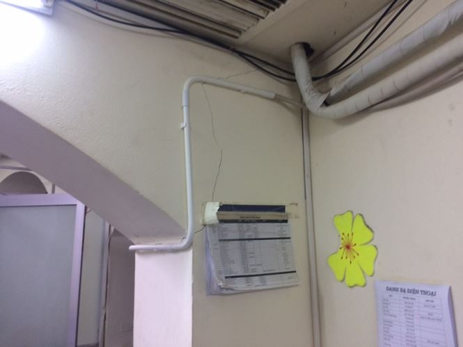 Những bức tường chằng chịt dây dẫn và ống điều hoà đã bị nứt theo thời gian, được tận dụng làm bảng chấm công, danh bạ điện thoại.