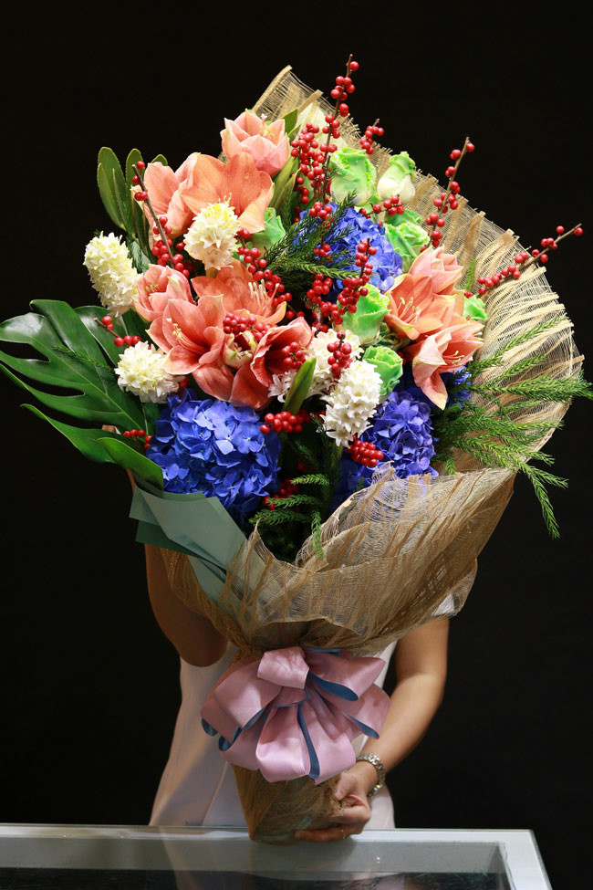 Bó hoa nhập rất lớn có giá tới 8 triệu đồng gồm hoa cẩm tú cầu nhập màu xanh tím lạ mắt, hoa lan tứ diện màu cam, hoa dạ lan hương màu trắng, hoa đông đào màu đỏ, hoa hồng phủ màu xanh lá cây nhập từ Hà Lan. (Ảnh: Dân Việt).