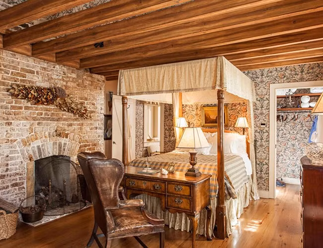 Phòng ngủ với giấy dán tường hoa văn và lò sưởi bằng gạch.