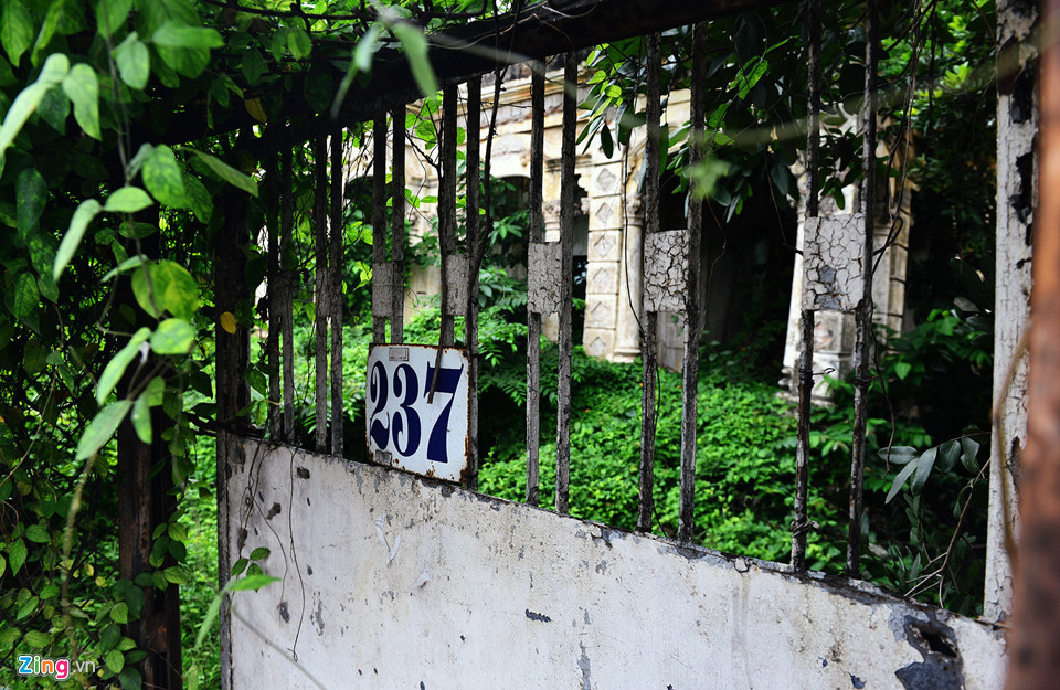 Sau gần 2 năm bỏ hoang, số nhà căn biệt thự vẫn còn hiện hữu ngay giữa chiếc cổng sắt với 2 giây xích khóa chắc chắn. Theo người dân bên căn nhà, do lâu ngày cây cỏ mọc um tùm nên khu vực này xuất hiện rất nhiều muỗi, bên trong họ còn thấy xuất hiện cả rắn, bọ cạp, không ai dám vào.