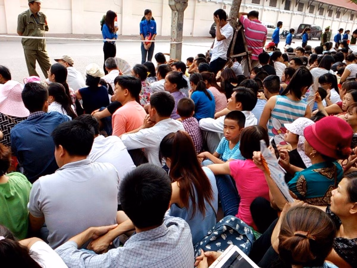 Người dân ngồi ngay ngắn đằng sau dải phân cách với sự bảo đảm trật tự đội thanh niên tình nguyện cùng lực lượng dân quân tự vê, công an.