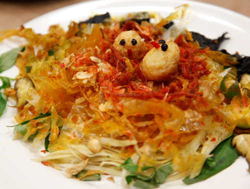 Bánh tráng trộn là món ăn vặt có nguyên liệu khá đơn giản nhưng lại rất ngon và hấp dẫn. Suất ăn bao gồm ít bánh tráng cắt sợi đem trộn cùng tôm khô chiên mỡ, phổi bò cháy, rau răm, đu đủ chua sợi, sốt tương, đậu phộng, mắm me sốt chua ngọt cùng vài cọng rau răm. Giá của món bánh tráng trộn là 5.000 - 8.000 đồng/bịch. Ảnh: tin12h