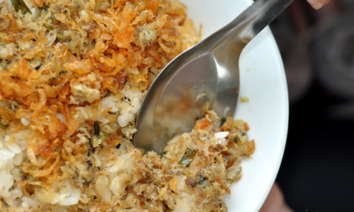 Tiếp theo, đổ đều cá đã xào lên mặt xôi, thêm ít mỡ gà rồi đảo đều cho cá và xôi quyện vào nhau. Khi ăn rắc thêm chút rau răm, mùi tàu, hành phi thơm. Ảnh: zing