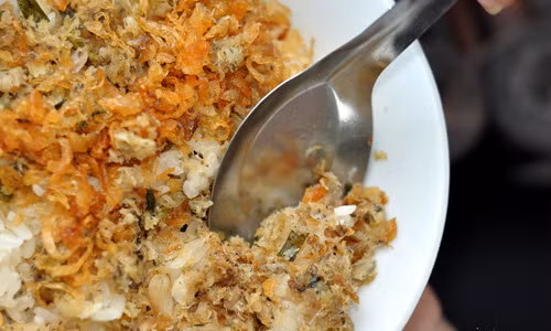 Tiếp theo, đổ đều cá đã xào lên mặt xôi, thêm ít mỡ gà rồi đảo đều cho cá và xôi quyện vào nhau. Khi ăn rắc thêm chút rau răm, mùi tàu, hành phi thơm. Ảnh: zing