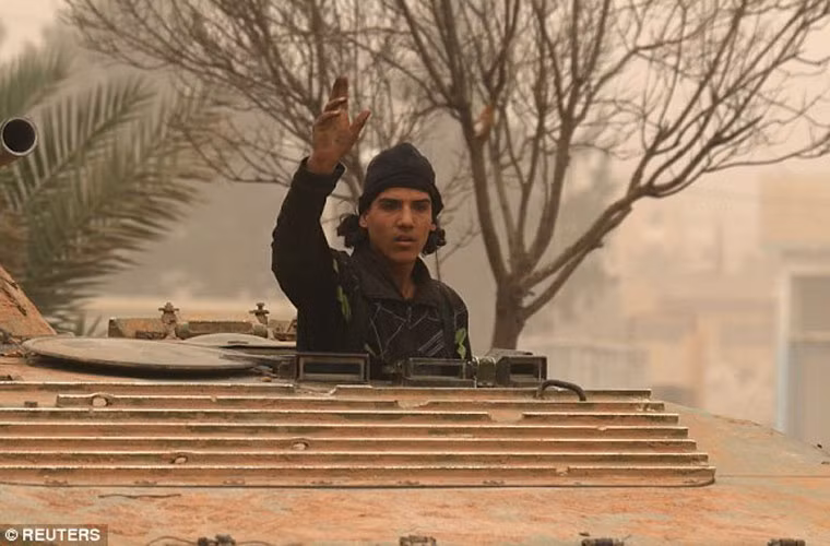 Một chiến binh nổi dậy Syria đứng trong xe bọc thép BMP đang trên con đường ở Dahiyat al-Assad, phía tây thành phố Aleppo. Ảnh Daily Mail