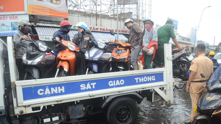 Lực lượng CSGT quận Bình Tân giúp người dân đẩy xe chết máy qua đoạn ngập.