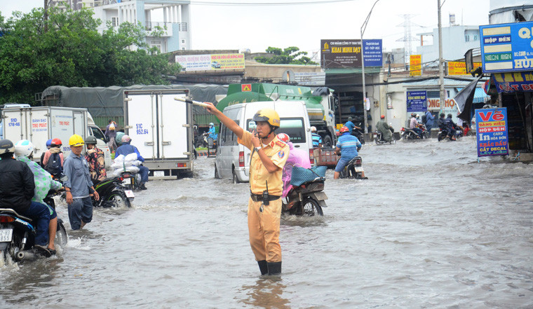 Lực lượng CSGT dầm dưới mưa, đường ngập nước để điều tiết giao thông.